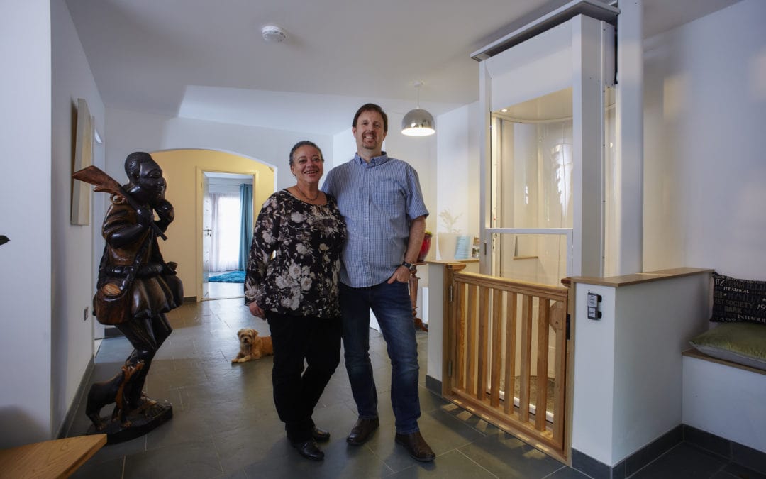 A husband and wife proudly standing in front of the home lift they had installed in their property.