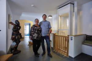 A husband and wife proudly standing in front of the home lift they had installed in their property.